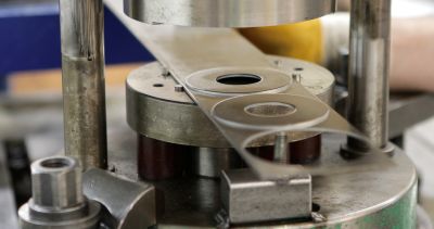 Industrial machine press forming precision flat washers from metal stock.