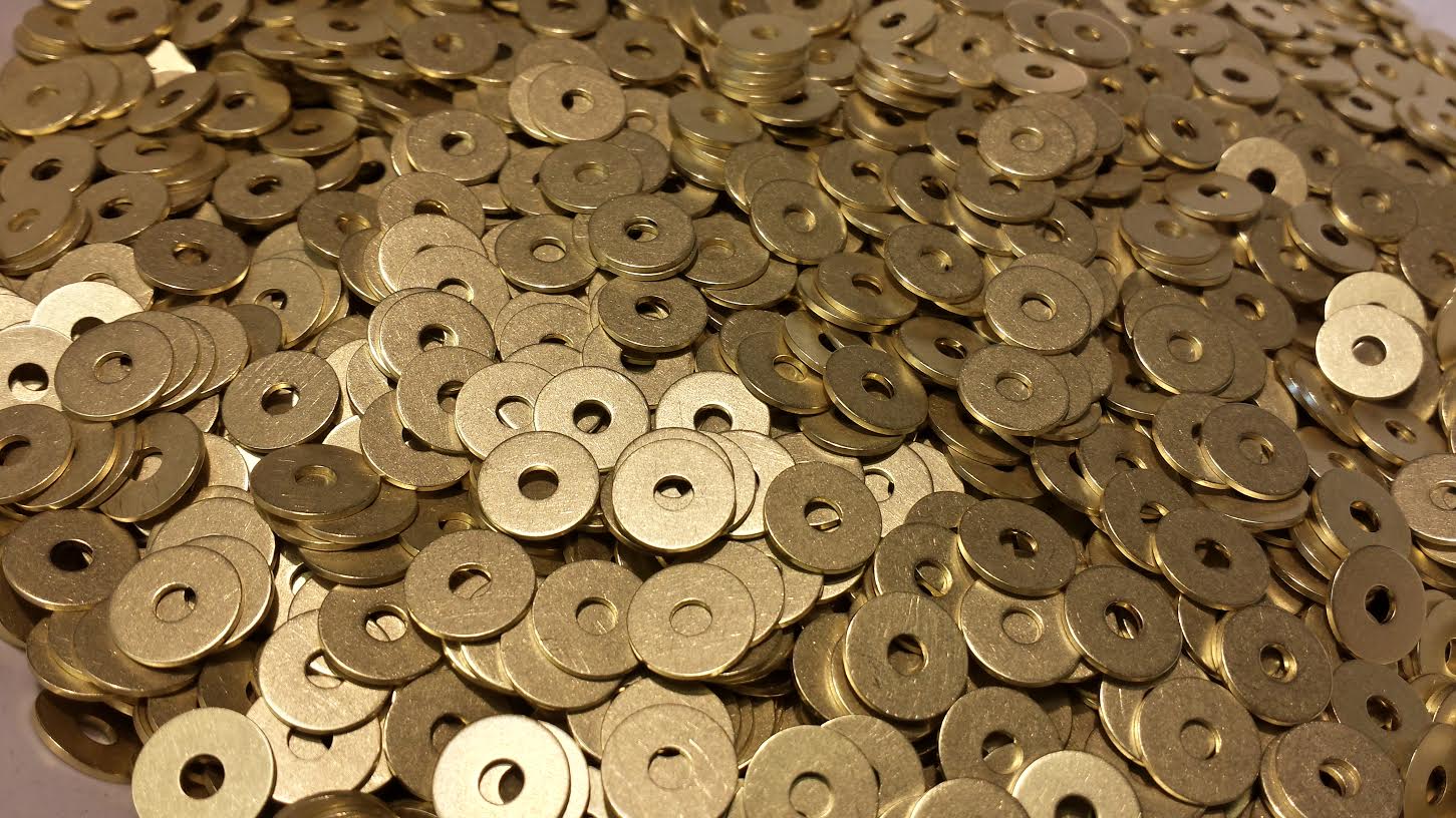 Bulk lot of custom brass washers stacked and scattered, highlighting the characteristic golden color of brass alloy.