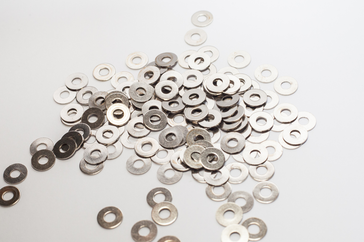 Assortment of custom stainless steel washers spread across a white background.
